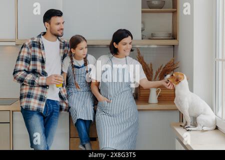 Die fröhliche Familie mit ihrem Hund genießt einen Moment in der Küche. Stockfoto