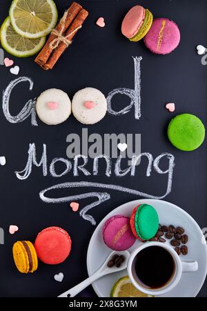 Wunderschöne Tafel mit den Worten Guten Morgen in einer schönen Schrift. Macarons und eine Tasse Kaffee, ideal für eine Bäckerei oder ein Café Stockfoto