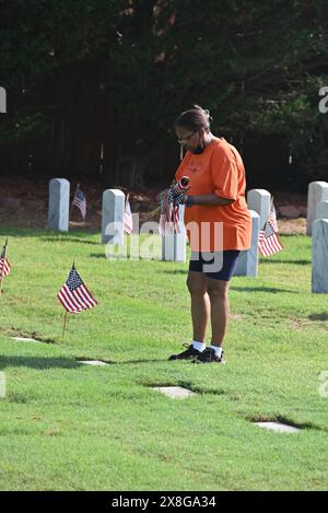 Raleigh, NC, USA, 25. Mai 2024; Donna Crawford aus Raleigh schließt sich freiwilligen Helfern an, die die 6.000 Grabsteine auf dem Raleigh National Cemetery vor den Feiertagen des Memorial Day mit Fahnen versehen. Donna nimmt seit 20 Jahren an der jährlichen Veranstaltung Teil, um die amerikanischen Männer und Frauen zu ehren, die in Friedenszeiten und Krieg im US-Militär gedient haben. Der Raleigh National Cemetery umfasst die Grabstätten von Soldaten aus dem Bürgerkrieg bis zu den Kriegen im Irak und Afghanistan. Credit D Guest Smith / Alamy Live News Stockfoto