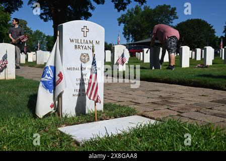 Raleigh, NC, USA, 25. Mai 2024; eine Flagge wird vor der Gedenkfeiertage auf dem Raleigh National Cemetery an der Markierung des Empfängers der Ehrenmedaille, William Bryant, angebracht. Die jährliche Veranstaltung, die von der Raleigh American Legion organisiert wird, ehrt die amerikanischen Männer und Frauen, die in Friedenszeiten und Krieg im US-Militär gedient haben. Der Raleigh National Cemetery umfasst die Grabstätten von Soldaten aus dem Bürgerkrieg bis zu den Kriegen im Irak und Afghanistan. Credit D Guest Smith / Alamy Live News Stockfoto