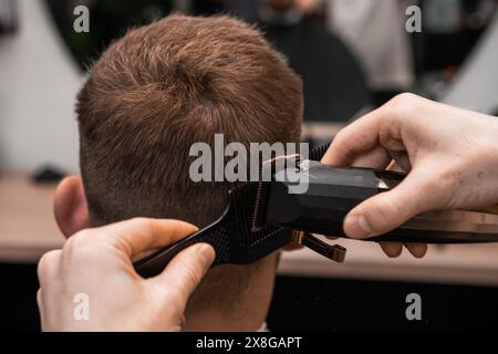 Der Friseur rasiert die Haare des Mannes auf der Straße im zeitgenössischen Friseur Stockfoto
