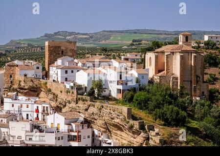 Die Kirche Parroquia de Nuestra Señora de la Encarnación und die Überreste der maurischen Burg auf dem Hügel über dem einzigartigen Pueblos blanco von Setenil de las Bodegas, Spanien. Die Bewohner des kleinen Dorfes Setenil leben seit dem neolithikum in Höhlenhäusern. Stockfoto