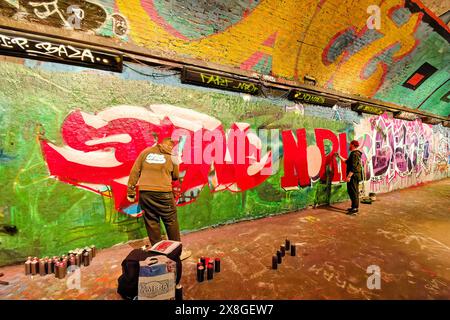 London Leake Street der Graffiti Tunnel zwei Künstler malen Bilder in dem farbenfrohen dunklen Tunnel Stockfoto