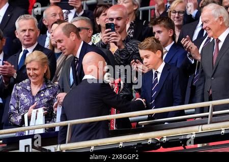 Manchester United-Trainer Erik Ten Hag (links) schüttelt Prince George die Hand, nachdem er das Finale des Emirates FA Cup im Wembley Stadium in London gewonnen hat. Bilddatum: Samstag, 25. Mai 2024. Stockfoto