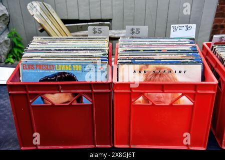 Ottawa, Kanada – 25. Mai 2024: Milchbehälter mit Alben, darunter Elvis Presley und Rod Stewart, zum Verkauf beim jährlichen Glebe Neighborhood Garage Sale, der für mehrere Blöcke in der Glebe Gegend in Ottawa, Ontario stattfindet. Milchkartons waren beliebte Aufbewahrungsmethoden für Alben. Stockfoto