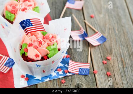 Patriotischer Cupcake 4. juli mit amerikanischer Flagge. Köstlicher Cupcake mit Frischkäse und blauem und rotem Topf auf altem hölzernem Hintergrund. Dessertessen für Stockfoto