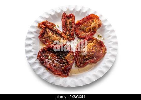 Getrocknete Tomaten in Öl mit Oregano in weißer Papierplatte isoliert auf weiß mit Schnittpfad Stockfoto