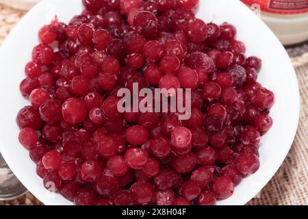 Gefrorene Preiselbeeren auf einer weißen Keramikplatte. Nahaufnahme. Stockfoto