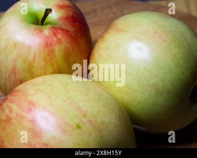 Frisches Apple Trio. Drei Äpfel in Rot- und Grüntönen auf einer Holzoberfläche, die natürliche Frische vermitteln. Stockfoto