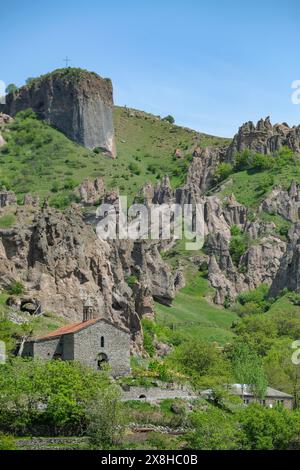 Goris, Armenien - 2. Mai 2024: Kirche des Heiligen Hripsime mit mittelalterlichen Höhlenwohnungen im Hintergrund in Alt-Goris, Armenien. Stockfoto