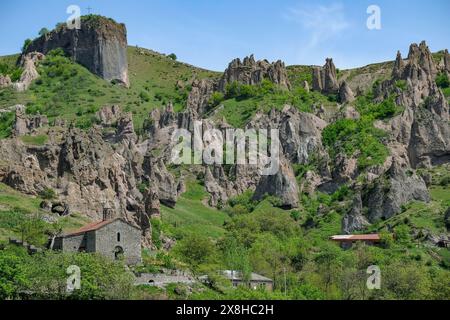 Goris, Armenien - 2. Mai 2024: Kirche des Heiligen Hripsime mit mittelalterlichen Höhlenwohnungen im Hintergrund in Alt-Goris, Armenien. Stockfoto