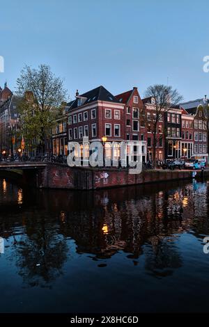 Niederlande, Amsterdam - 10. April 2024: Amsterdamer Grachtenhäuser, Fahrräder und Brücken in der Abenddämmerung im Stadtteil Jordaan Stockfoto