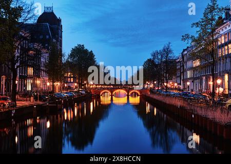 Niederlande, Amsterdam - 10. April 2024: Amsterdamer Grachtenhäuser, Fahrräder und Brücken in der Abenddämmerung im Stadtteil Jordaan Stockfoto