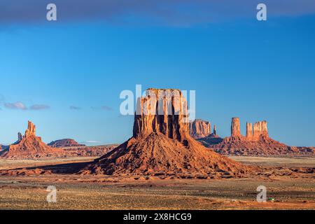 Der berühmte Merrick Butte im Monument Valley während des Sonnenuntergangs zeigt die komplexen Erosionsmuster im weichen Felsen und eine riesige Weite des zerklüfteten Geländes. Stockfoto