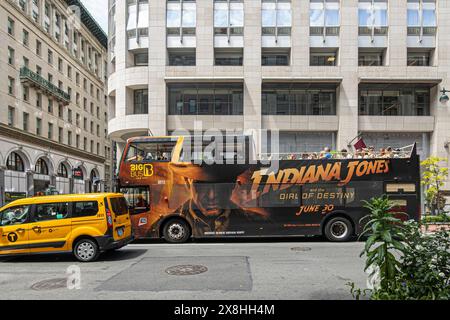 New York, NY, USA - 2. August 2023: Big Bus Hop on Hop off auf Madison mit Indiana Jones, Dial of Destiny Film, Werbung. Gelbes Taxi vor dem Hotel Stockfoto