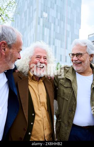 Eine Gruppe von drei reiferen kaukasischen Männern genießt es, gemeinsam spazieren zu gehen und im Freien zu lachen Stockfoto