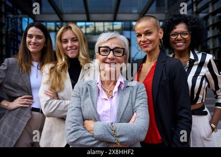 Porträtgruppe formelle Geschäftsfrauen unterschiedlichen Alters, die im Freien gemeinsam in die Kamera lächeln. Stockfoto