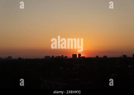 Orangefarbener Sonnenuntergang - Silhouette der Skyline der Stadt - dunkle Konturen der Gebäude im Kontrast zum verblassten Licht. Aufgenommen in Toronto, Kanada. Stockfoto