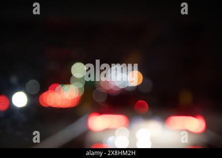 Nahaufnahme - Unschärfe, bunte Bokeh-Lichter - dunkler Hintergrund - Rot, weiß prominent - Nachtszene - Stadt, Ampelatmosphäre - weicher Fokus. Aufgenommen Stockfoto