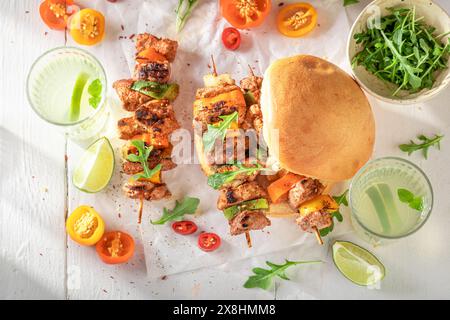Leckerer gerösteter Schaschlik mit Brötchen, gebacken auf einem gegrillten. Gegrillter Spieß mit Brötchen und Gemüse. Stockfoto