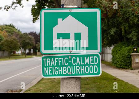 Grün-weißes Schild - VERKEHRSBERUHIGTE NACHBARSCHAFT - Haussymbol - Metallmast - Vorstadtstraße vor dem Hintergrund. Aufgenommen in Toronto, Kanada. Stockfoto