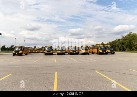 Gelbe Schulbusse standen auf einem leeren Parkplatz - unter teilweise bewölktem Himmel. Aufgenommen in Toronto, Kanada. Stockfoto