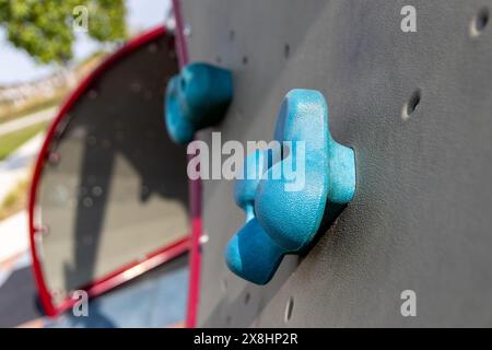Nahaufnahme der blauen Klettergriffe - graue Wand - Spielplatz im Freien. Aufgenommen in Toronto, Kanada. Stockfoto