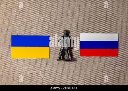 Die Figur eines Soldaten auf dem Hintergrund der Fahnen Russlands und der Ukraine Stockfoto