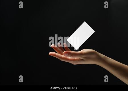 Frau mit leerer Visitenkarte auf schwarzem Hintergrund, Nahaufnahme. Modell für Design Stockfoto