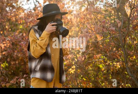 Frau, mit Liebe zum Detail und der Schönheit der Natur, macht Fotos im Herbstwald, um ihre erstaunlichen Momente und Emotionen in ihr zu vermitteln Stockfoto