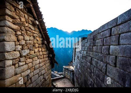 Sonnenaufgang zwischen Bäumen und Inkaruinen mit den Berggipfeln der Anden im Hintergrund in der östlichen Kordillera im Süden Perus Stockfoto