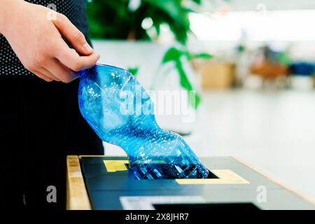 Hand eines jungen Mannes, der Plastikflasche in den Mülltonnen wirft Stockfoto