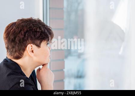 Eine besinnliche, übergroße Frau mit einer Hand am Kinn blickt nachdenklich aus dem Fenster auf die Stadt, umgeben von einem weichen Vorhang, tief ich Stockfoto