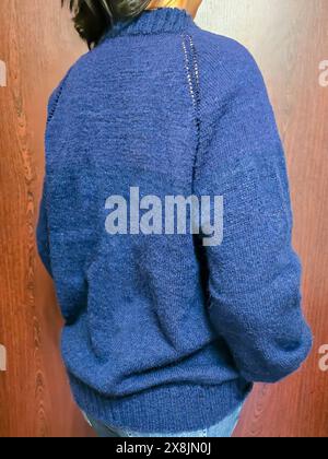 Handgefertigte Strickwaren. Strickstoff aus dunklen Garnen. Pullover für Frauen. Kopierbereich Stockfoto