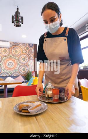 Die marokkanische Kellnerin serviert an einem Tisch in einem marokkanischen Teeladen Stockfoto
