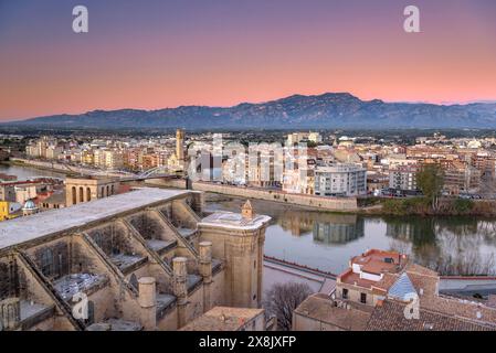 Tortosa bei Sonnenaufgang, von der Burg Suda aus gesehen. Im Vordergrund die Kathedrale und der Fluss Ebro. Im Hintergrund die Häfen (Tarragona, Spanien) Stockfoto