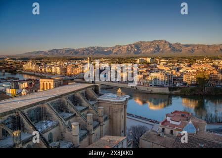 Tortosa bei Sonnenaufgang, von der Burg Suda aus gesehen. Im Vordergrund die Kathedrale und der Fluss Ebro. Im Hintergrund die Häfen (Tarragona, Spanien) Stockfoto