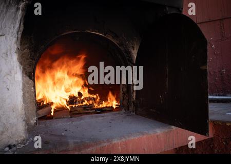 Feuer und verbrenne Kohle im Steinofen. Ofen aus Ziegeln und Ton. Stockfoto