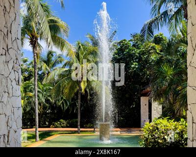 Wunderschöner Brunnen eines Swimmingpools in einem Luxusresort-Hotel in der Karibik, mit einem breiten Wasserstrahl inmitten der tropischen Vegetation Stockfoto