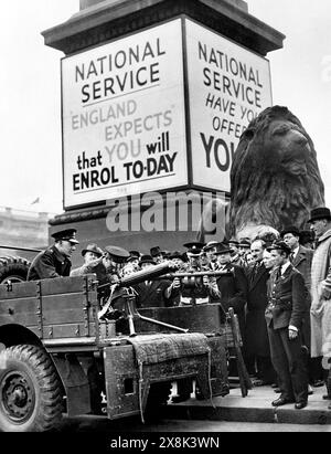 NUR SCHWARZWEISS-AKTENFOTO vom 09/39, auf dem Soldaten beobachtet wurden, die ein Vickers-Maschinengewehr und einen Entfernungsfinder unter einem Poster für den nationalen Dienst am Trafalgar Square als Teil einer großen Rekrutierungsfahrt zu Beginn des Zweiten Weltkriegs demonstrierten. Jugendliche würden nicht ins Gefängnis geschickt, weil sie sich dem von den Tories vorgeschlagenen "obligatorischen" nationalen Dienst widersetzen, sagte James geschickt, da Labour die Politik als "Gimmick" bezeichnet. Ausgabedatum: Sonntag, 26. Mai 2024. Stockfoto