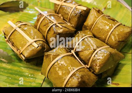 Thailändischer gedämpfter, gesüßter Kleberreis mit Füllung, die in Bananenblatt gewickelt ist, genannt Khao Tom Mud Stockfoto