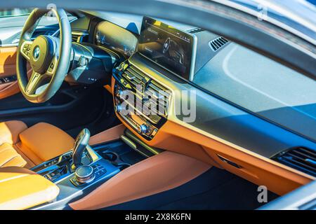 Nahaufnahme des Innenraums eines BMW i4 Elektroautos mit orangefarbenen Ledersitzen auf der Beifahrerseite. Stockfoto