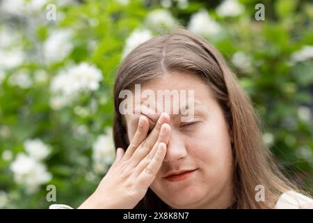 Junge Frau leidet an Heuschnupfen und reibt sich die Augen im Freien, Freiburg, Baden-Württemberg, Deutschland Stockfoto