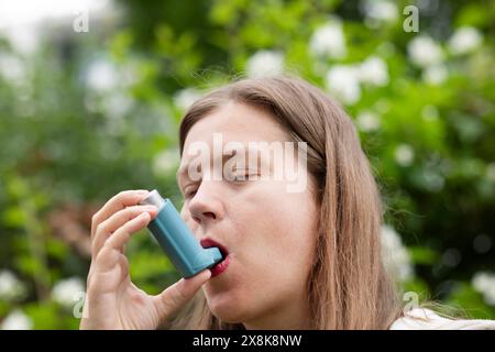 Junge Frau leidet an Heuschnupfen und inhaliert Asthmaspray im Freien, Freiburg, Baden-Württemberg, Deutschland Stockfoto