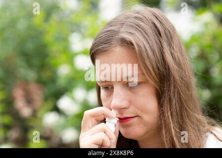 Junge Frau leidet an Heuschnupfen und sprüht im Freien Nase, Freiburg, Baden-Württemberg, Deutschland Stockfoto