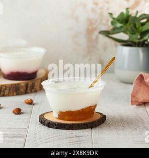 Köstlicher Joghurt mit Aprikosenmarmelade, wunderschön in einem klaren Plastikbecher serviert Stockfoto