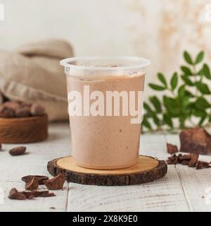Köstliches Schokoladenmousse in einem klaren Plastikbecher serviert auf einer rustikalen Holzuntersetzer. Stockfoto