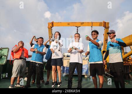 (240526) -- SANYA, 26. Mai 2024 (Xinhua) -- Mitarbeiter feiern, nachdem sie den Kurzflossen-Pilotwal „Haitang“ auf einem Forschungsschiff ins Meer gebracht haben, 26. Mai 2024. Am 3. Januar dieses Jahres wurde ein verletzter männlicher Kurzflossen-Grindwal in der Haitang Bay von Sanya gefunden. Es wurde zur Behandlung an das Sanya Haichang Animal Conservation Center geschickt und erhielt den Namen „Haitang“. Dank der akribischen Betreuung durch professionelle Züchter und Freiwillige erholt sich „Haitang“ gut und ist entschlossen, nach gründlicher Untersuchung und Bewertung wieder ins Meer zurückgelassen zu werden Stockfoto