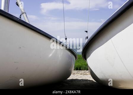 Zwei Segelboote befinden sich an einem Sandstrand mit Blick auf das ruhige Meer unter teilweise bewölktem Himmel. Stockfoto