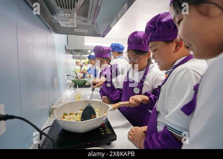 Xiong'an, chinesische Provinz Hebei. Mai 2024. Die Schüler kochen während eines kulinarischen Kurses an einer Grundschule in Xiong'an New Area, nordchinesischer Provinz Hebei, 22. Mai 2024. In den letzten Jahren hat Xiong'an New Area den hochwertigen Bildungsbau kontinuierlich gefördert. Das Gebiet hat ein innovatives Bildungsentwicklungssystem eingeführt, Bildungseinrichtungen mit hohem Standard errichtet und berufliche Bildungsressourcen eingeführt. Derzeit hat das Gebiet 717 Schulen mit 235.000 Schülern und 20.000 Lehrern. Quelle: Mu Yu/Xinhua/Alamy Live News Stockfoto